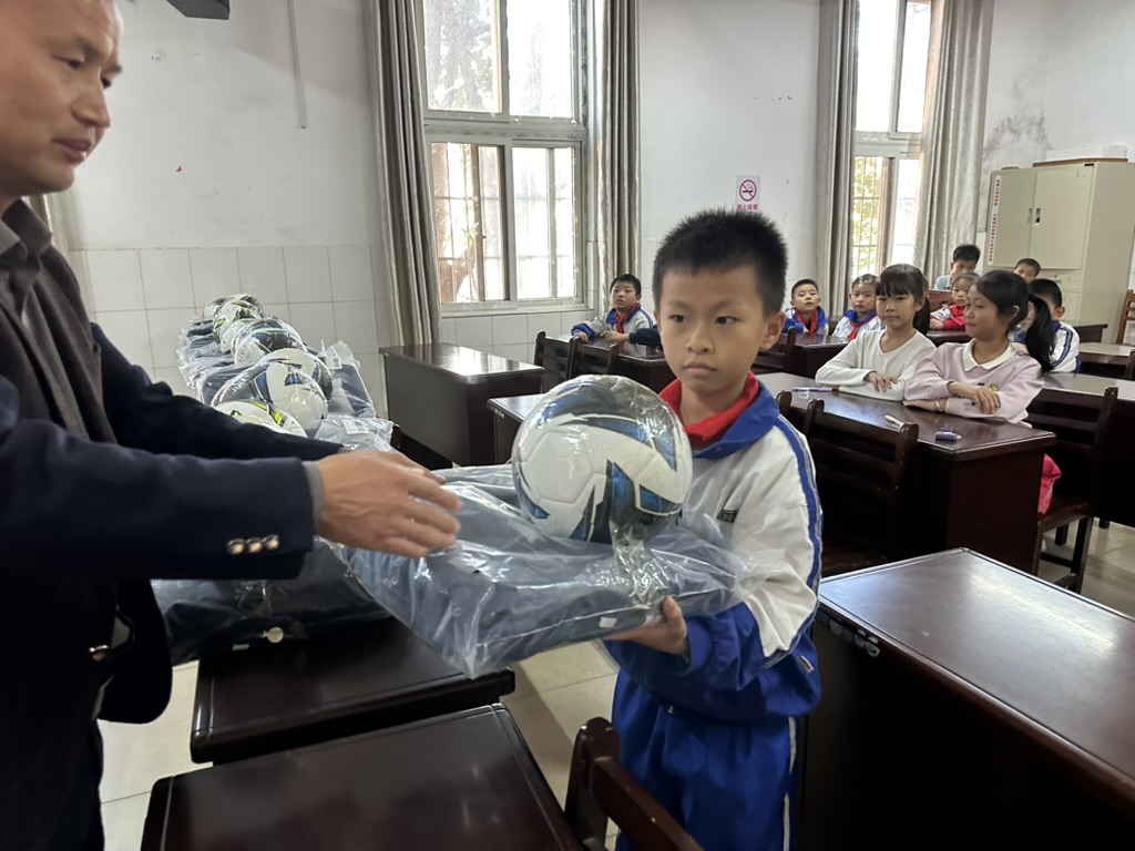 A student receiving donated sports and activity supplies in the classroom.